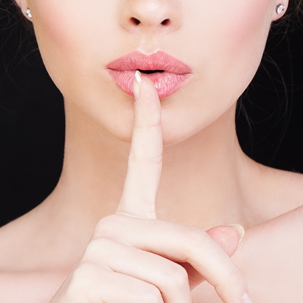 woman holding index finger to lips